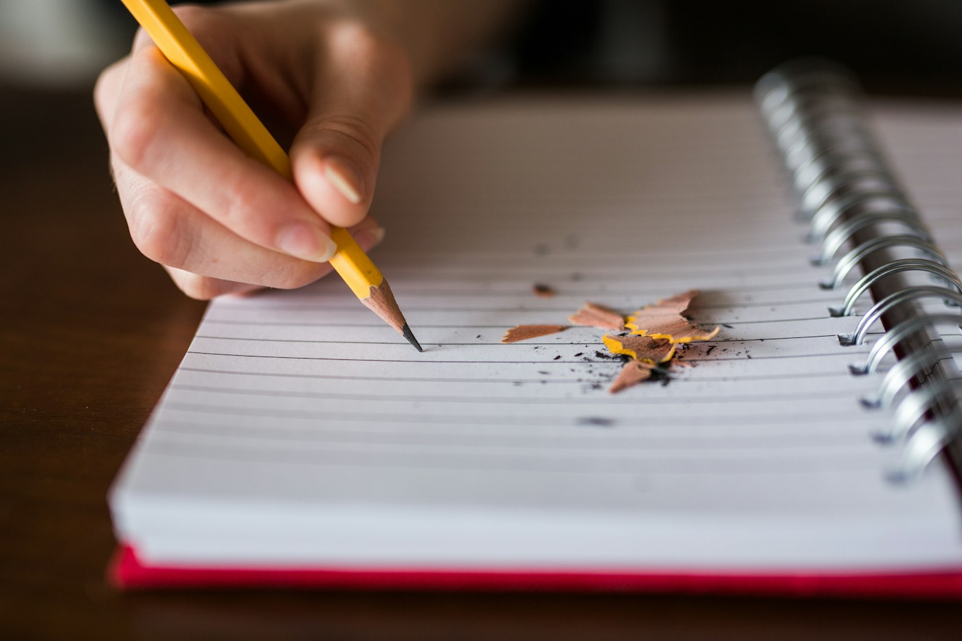 A hand writing with a pencil in an open notebook